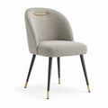 Chaise en tissu gris avec pieds en métal et détails dorés